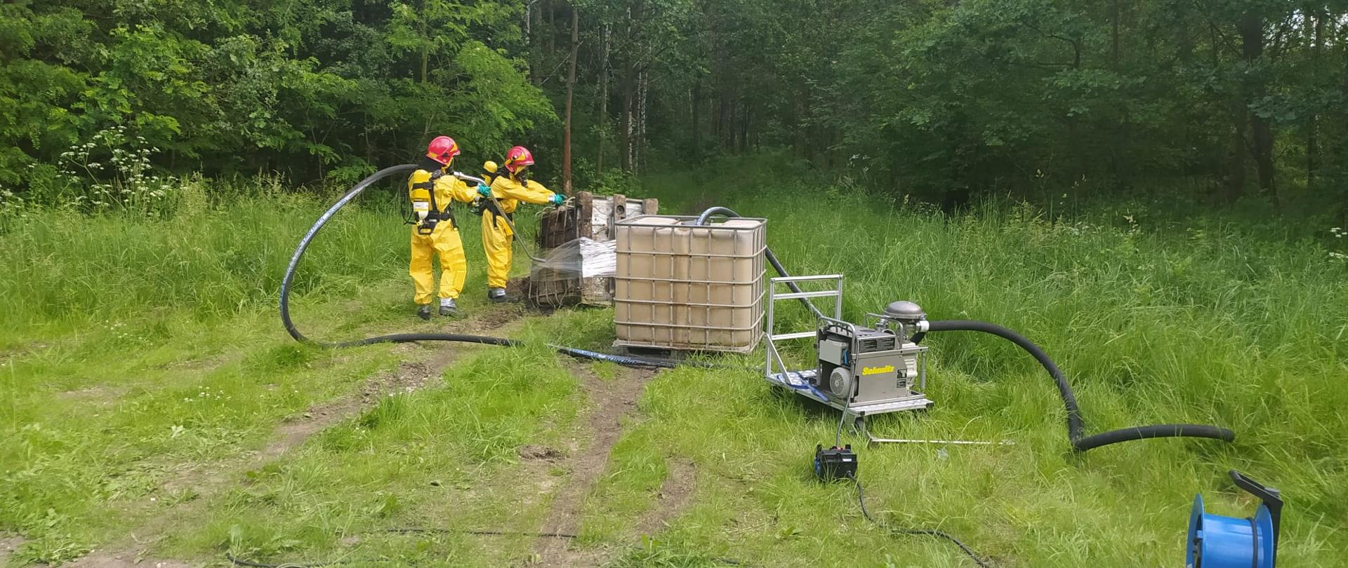 Zdjęcie przedstawia strażaków podczas działań związanych z przepompowywaniem substancji do zbiornika zastępczego
