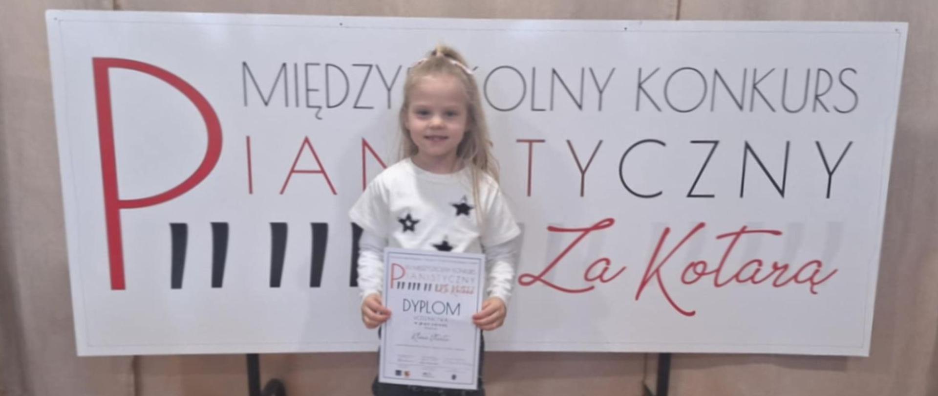 Klara Utrata stoi na tle planszy konkurs pianistyczny za kotarą