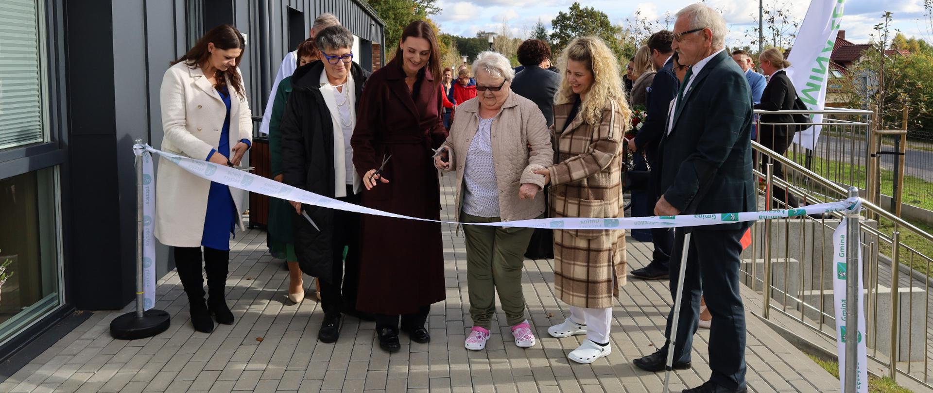 kilka osób przecina wstęgę symbolicznie otwierając centrum opiekuńczo mieszkalne 