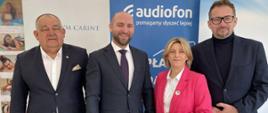 Osoby pozują do zdjęcia, za nimi znajdują się roll-upy partnerów wydarzenia