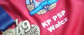 Zdjęcie przedstawia medal reprezentanta KP PSP w Wałczu na tle koszulki z logo KP PSP w Wałczu