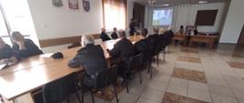 Na zdjęciu strażaków siedzących przy stołach podsumowujących ćwiczenia powiatowe „Mesko 2021”. Jeden z nich przedstawia prezentację z tych ćwiczeń oraz najważniejsze elementy, które byłby poruszane w późniejszej dyskusji.