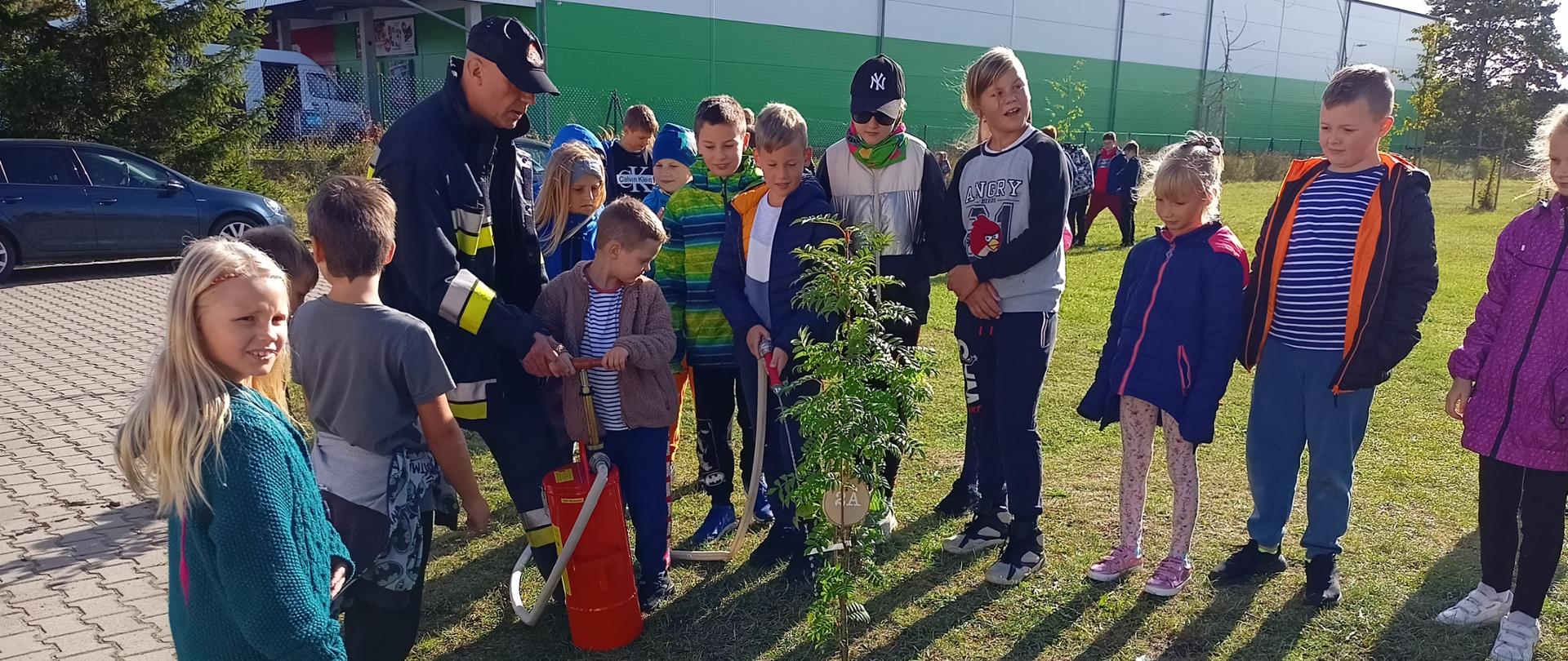 Dzieci podlewają drzewka z udziałem straży pożarnej
