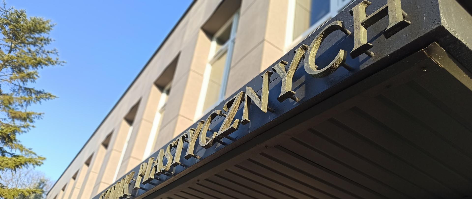 Fragment frontu budynku PLSP w Lublinie. Widoczne pierwsze piętro, okna biblioteki i auli. Poniżej napis Państwowe Liceum Sztuk Plastycznych