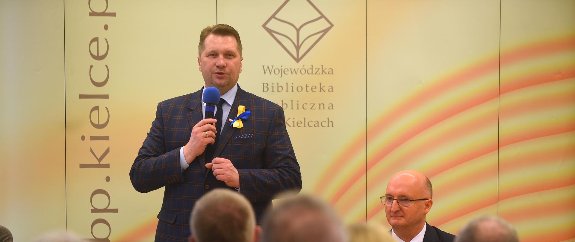 Spotkanie z samorządowcami w Kielcach. Minister przemawia do mikrofonu.