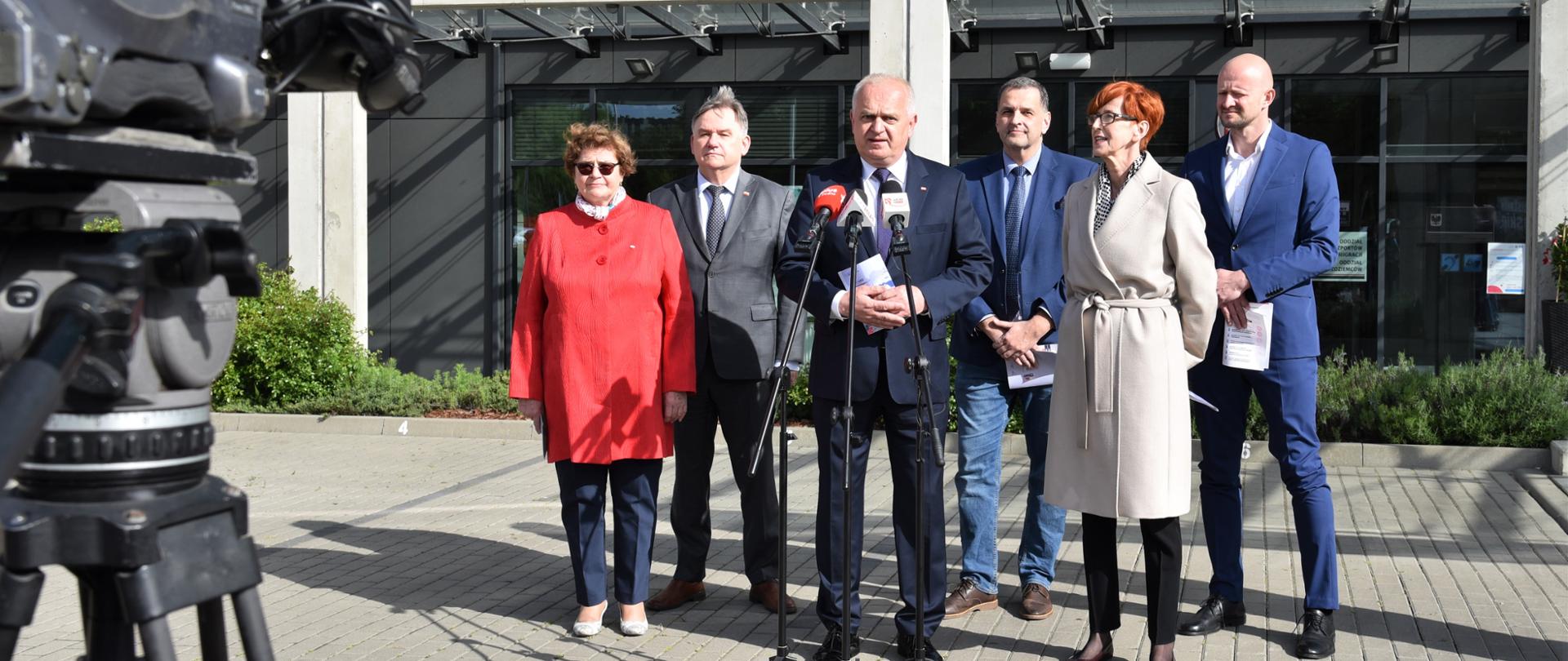 Na tle budynku Lubuskiego Urzędu Wojewódzkiego, przed rzędem mikrofonów stoją: wojewoda Władysław Dajczak, Europoseł Elżbieta Rafalska, Poseł Elżbieta Płonka, zastępca Głównego Inspektora Ochrony Środowiska Marek Surmacz, przewodniczący Rady Miasta Gorzowa Sebastian Pieńkowski i radny Tomasz Rafalski