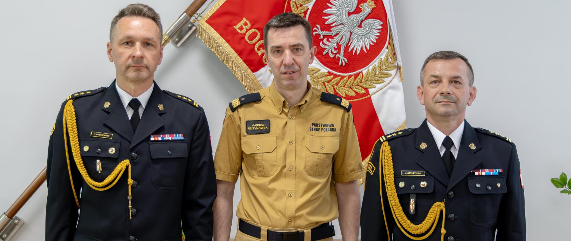 Zdjęcie pamiątkowe dwóch strażaków w mundurze galowym i jeden strażak w mundurze służbowym
