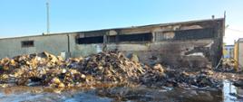 Zdjęcie przedstawia dogaszone baloty sprasowanej makulatury oraz uszkodzenia budynku magazynowego.