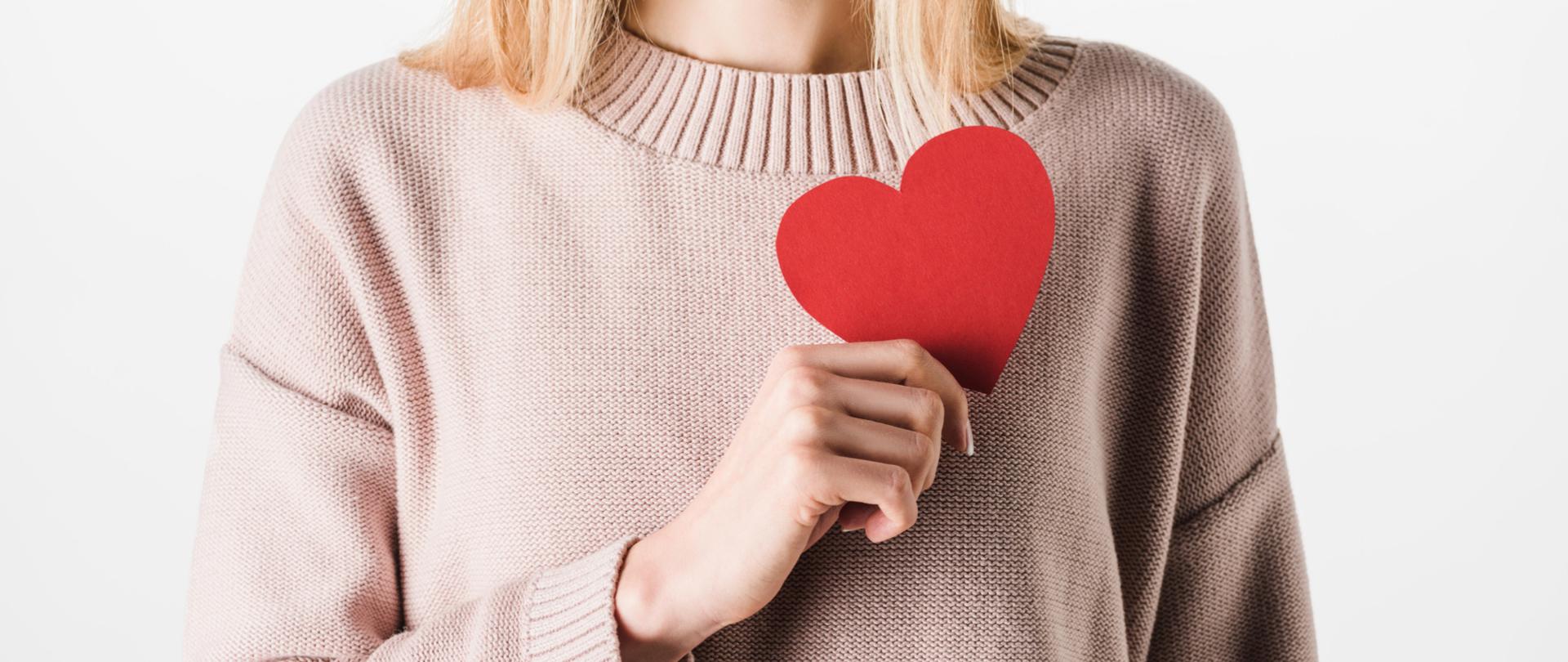 Na zdjęciu jest kobieta trzymająca serce. Tło jest białe.