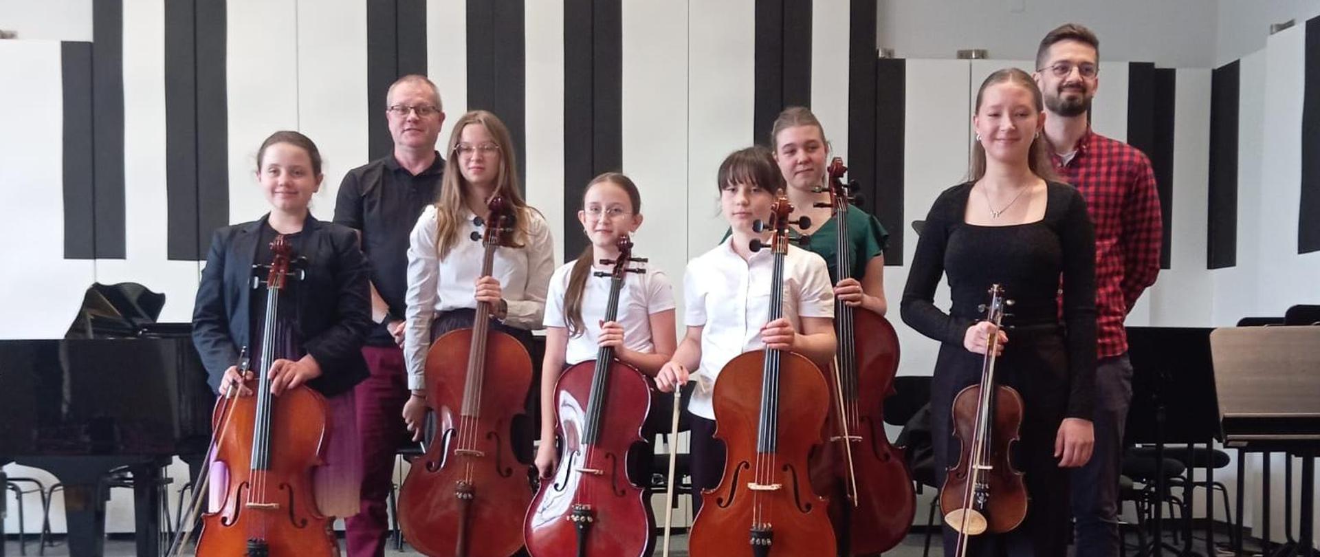 Sześć dziewcząt i dwóch mężczyzn stoi na scenie