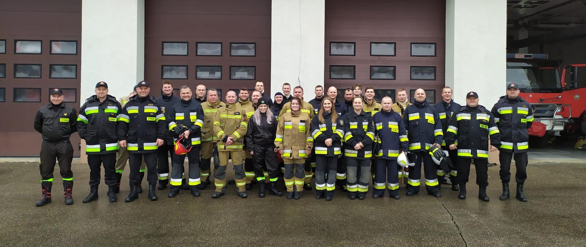 Fotografia przedstawia nowych strażaków ochotników po zdaniu egzaminów kursu podstawowego w asyście funkcjonariuszy z Komendy Powiatowej Państwowej Straży Pożarnej w Malborku.