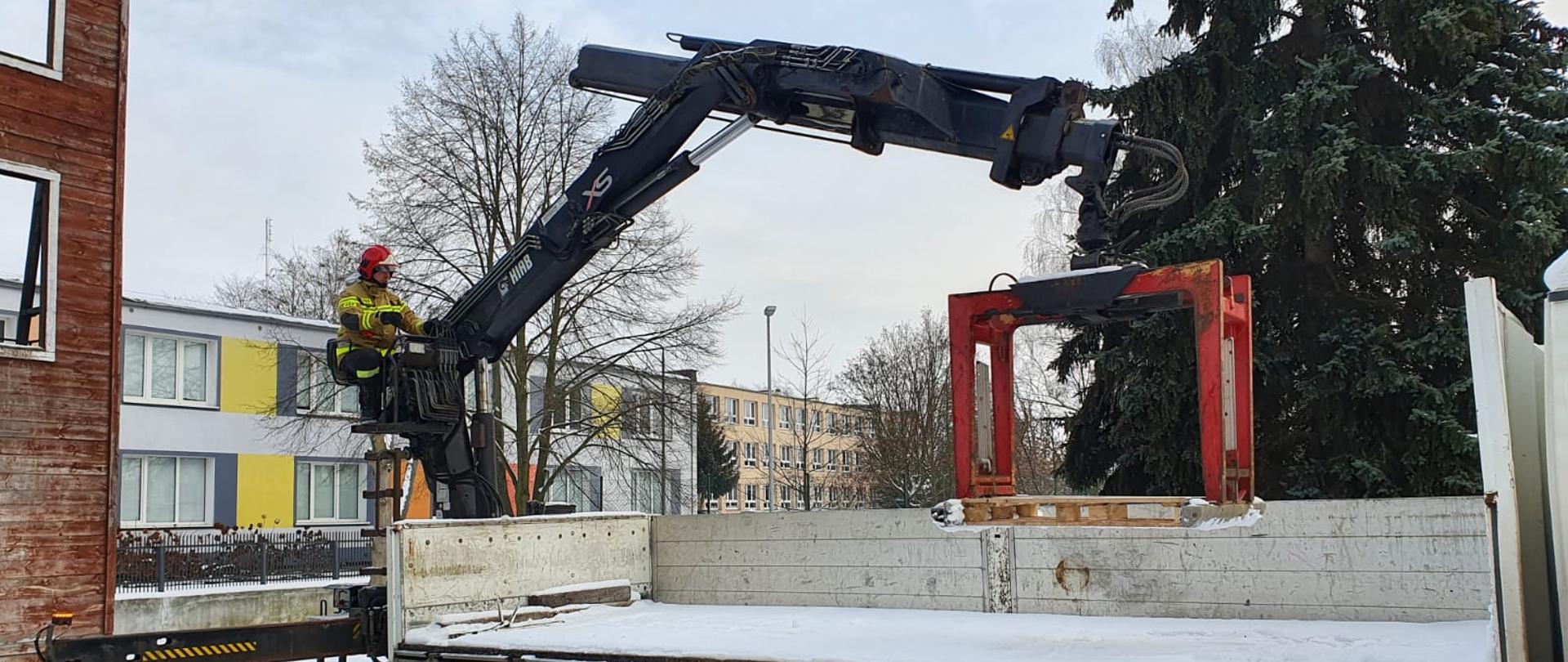 Widać strażaka, który obsługuje żuraw