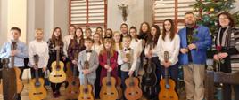 Zdjęcie przedstawia wszystkich wykonawców ( uczniów Kłodzkiej i Bystrzyckiej Szkoły Muzycznej ) z koncertu Najpiękniejsze polskie kolędy i pastorałki " - 7 stycznia 2023 wraz z nauczycielami klas gitary P. A. Kozakowskiej i P. W. Kozakowskim. Zdjęcie wykonane w Muzeum Ziemi Kłodzkiej, uczniowie trzymają gitarę