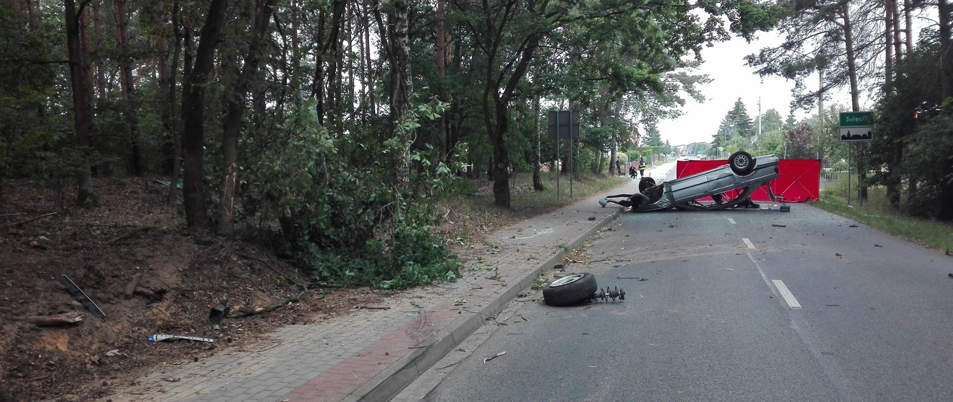 Na zdjęciu widać samochód leżący na dachu po wypadku