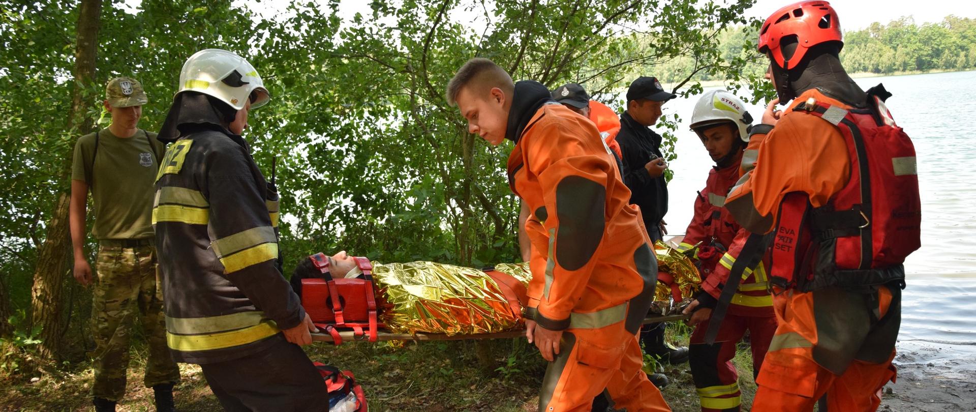 Strażacy ewakuują z wody osobę poszkodowaną.
