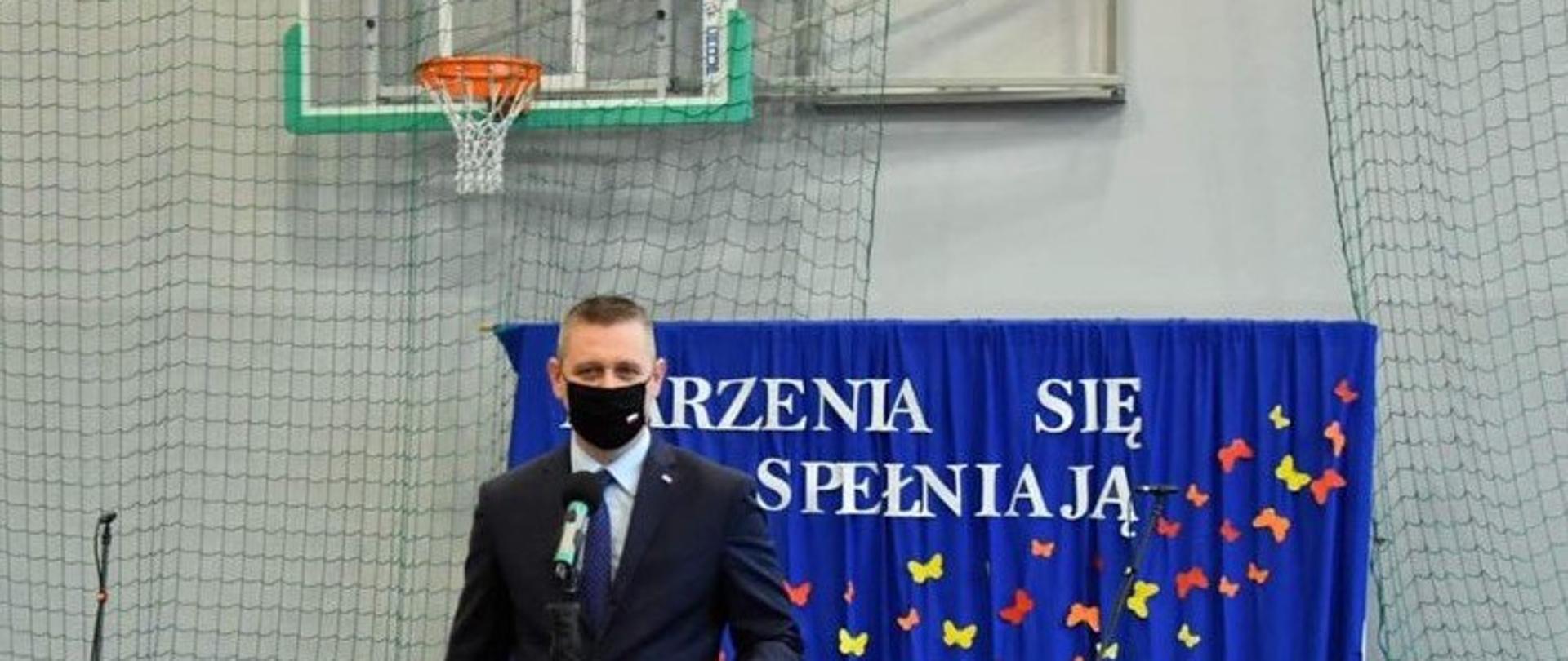 Elegancko ubrany mężczyzna przemawia podczas oddania do użytku sali gimnastycznej