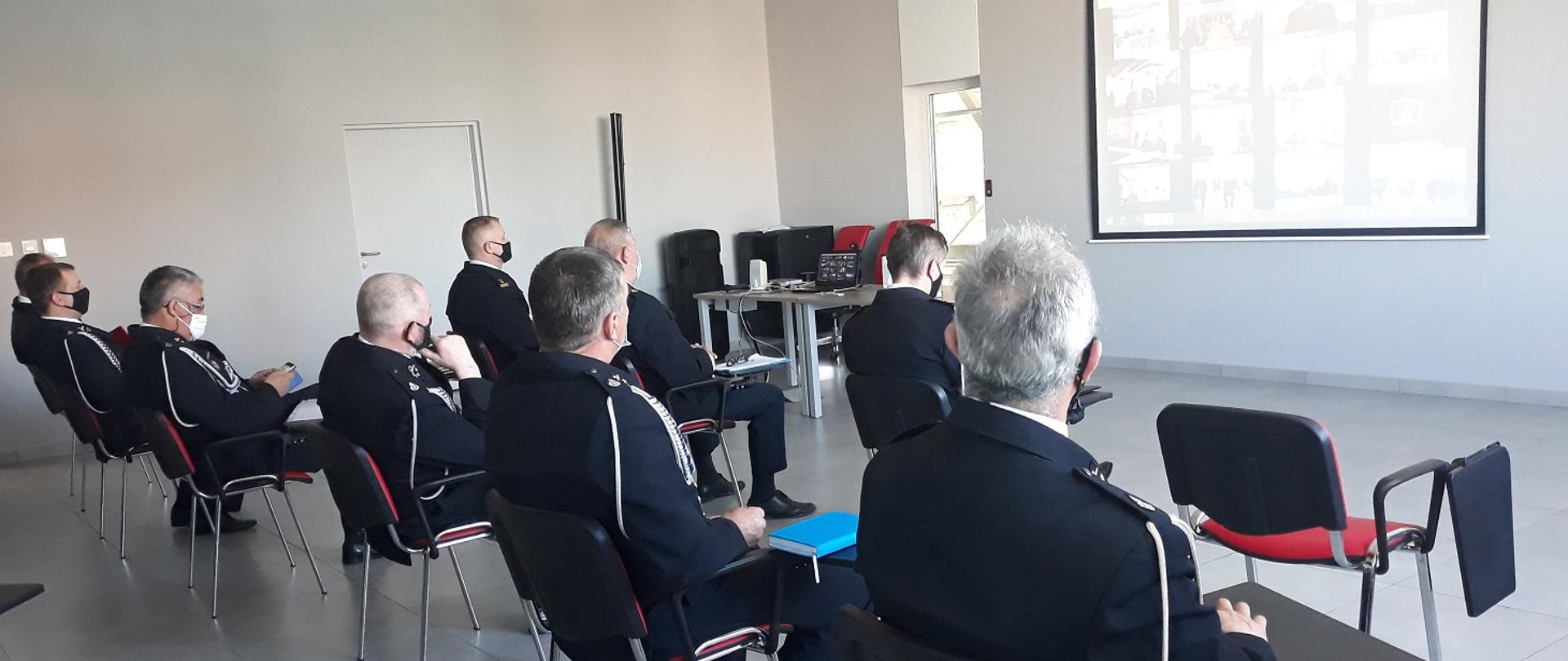 Zdjęcie obrazuje strażaków w mundurach wyjściowych podczas wideokonferencji 