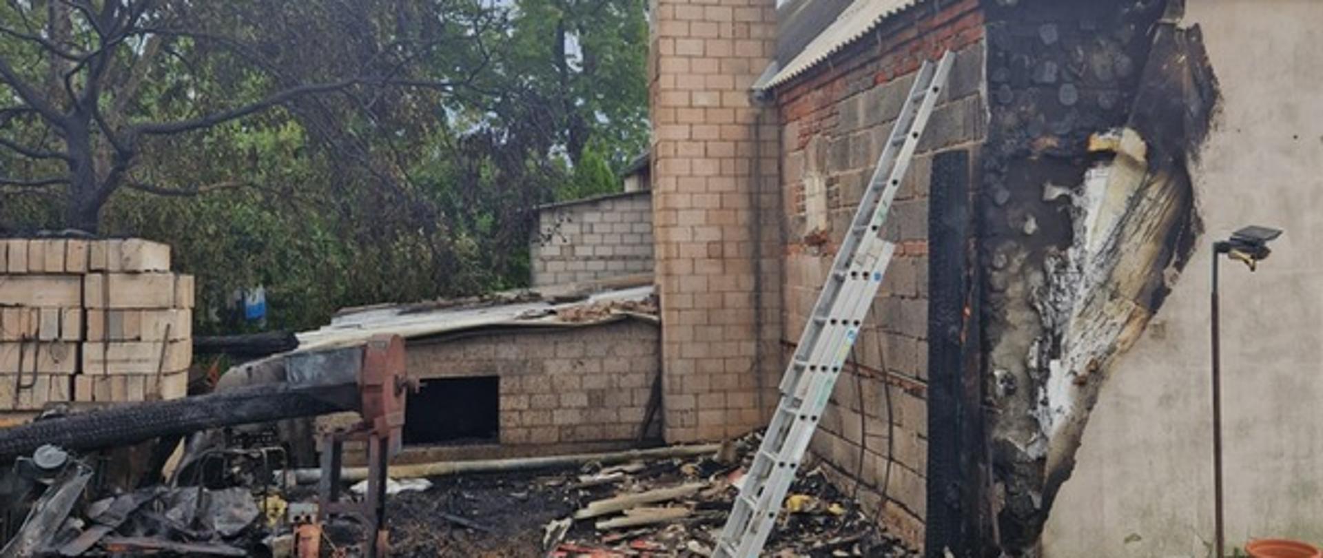 Pogorzelisko pożaru. Po prawej stronie częściowo nadpalone ocieplenie budynku mieszkalnego. Po lewej zgliszcza szopy