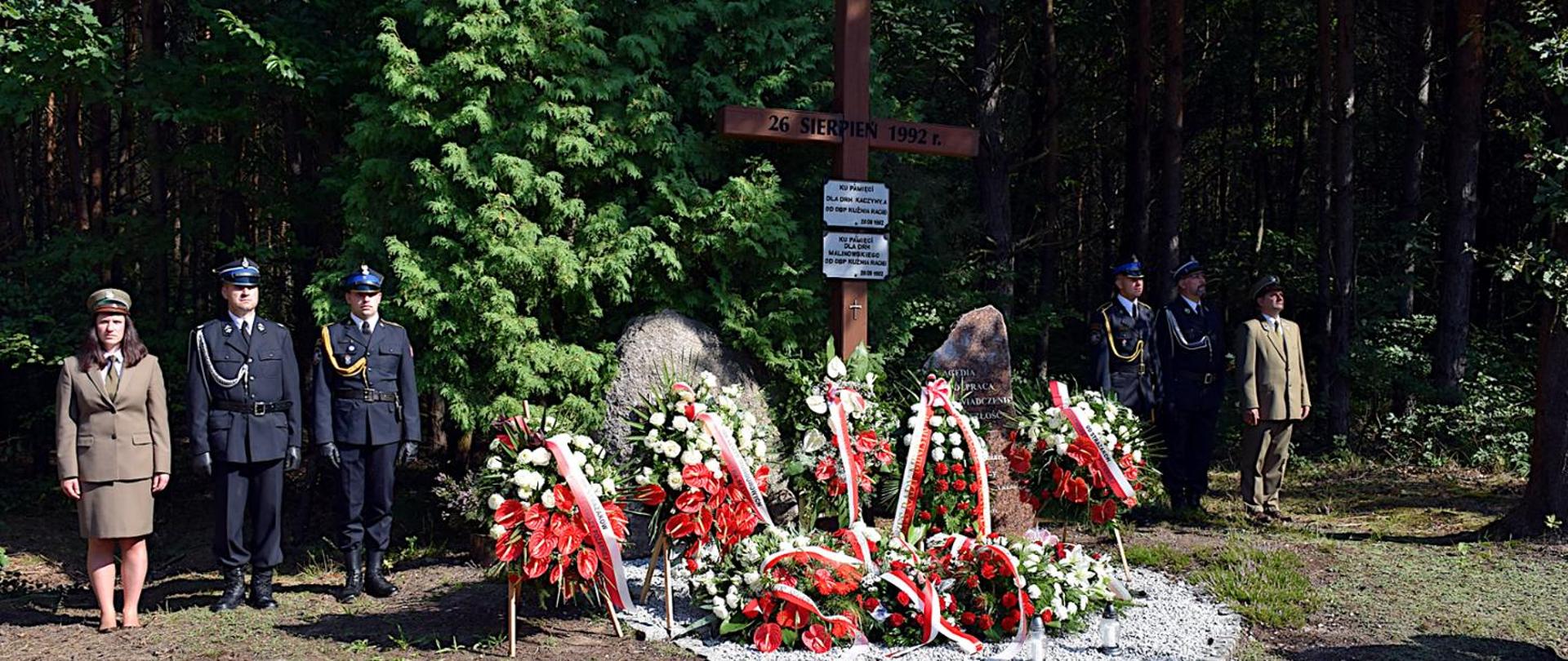 Strażacy PSP, OSP oraz leśnicy w ubraniach wyjściowych pełnią wartę przy symbolicznych kamieniach i krzyżu upamiętniających wielki pożar w Kuźni Raciborskiej.