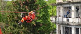 Strażak wiszący na linie pomiędzy budynkami