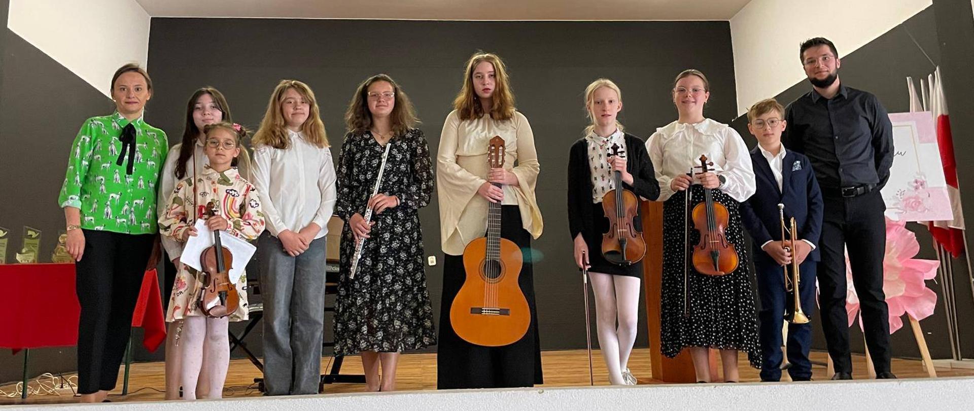 Uczniowie i nauczyciele stojący na scenie.