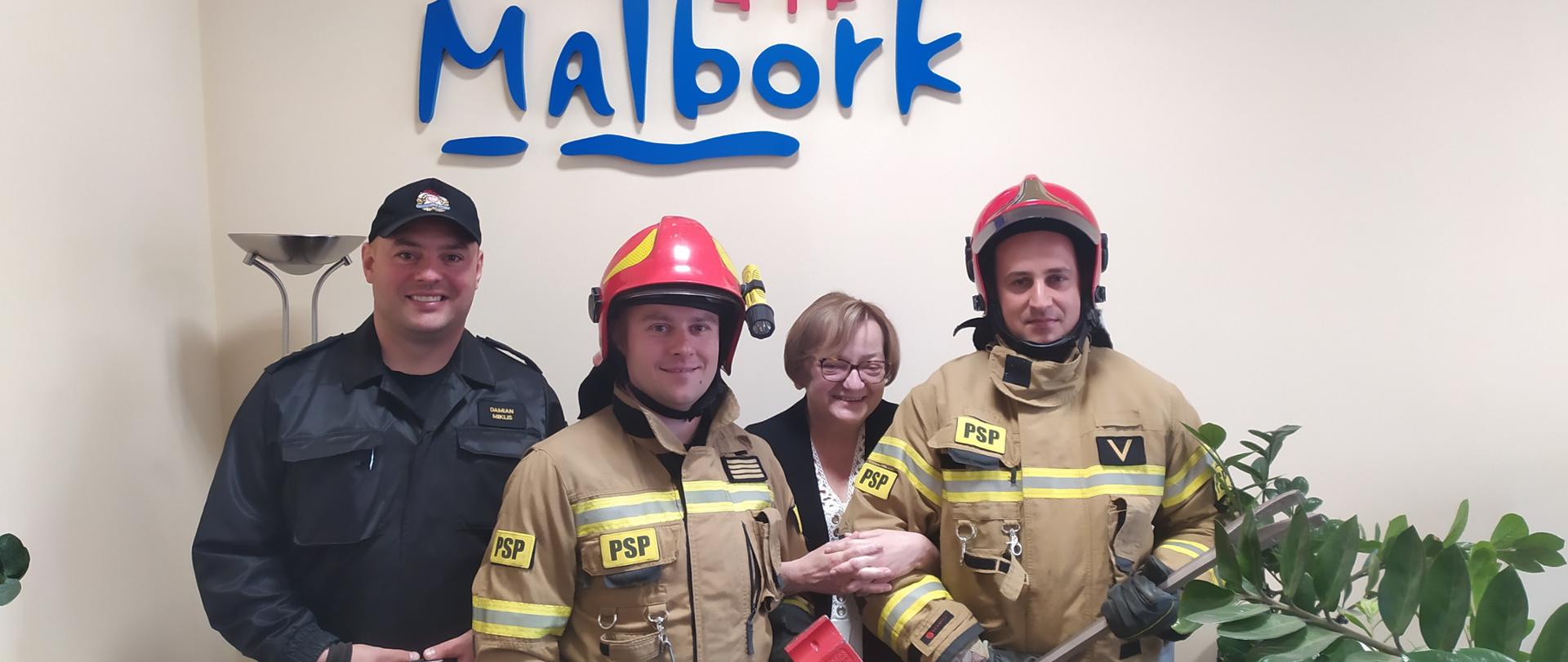 Fotografia przedstawia strażaków ustawionych do wspólnego zdjęcia z Panią Prezes TBS Malbork