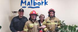 Fotografia przedstawia strażaków ustawionych do wspólnego zdjęcia z Panią Prezes TBS Malbork