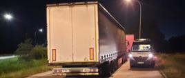 Od lewej: droga krajowa i stojące w zatoce kontrolnej dwa ciągniki siodłowe z podpiętymi naczepami kurtynowymi. Obok nich stoi oznakowany furgon mazowieckiej Inspekcji Transportu Drogowego.