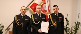 Troje strażaków po wręczeniu aktu nominacyjnego pozuje do zdjęcia,