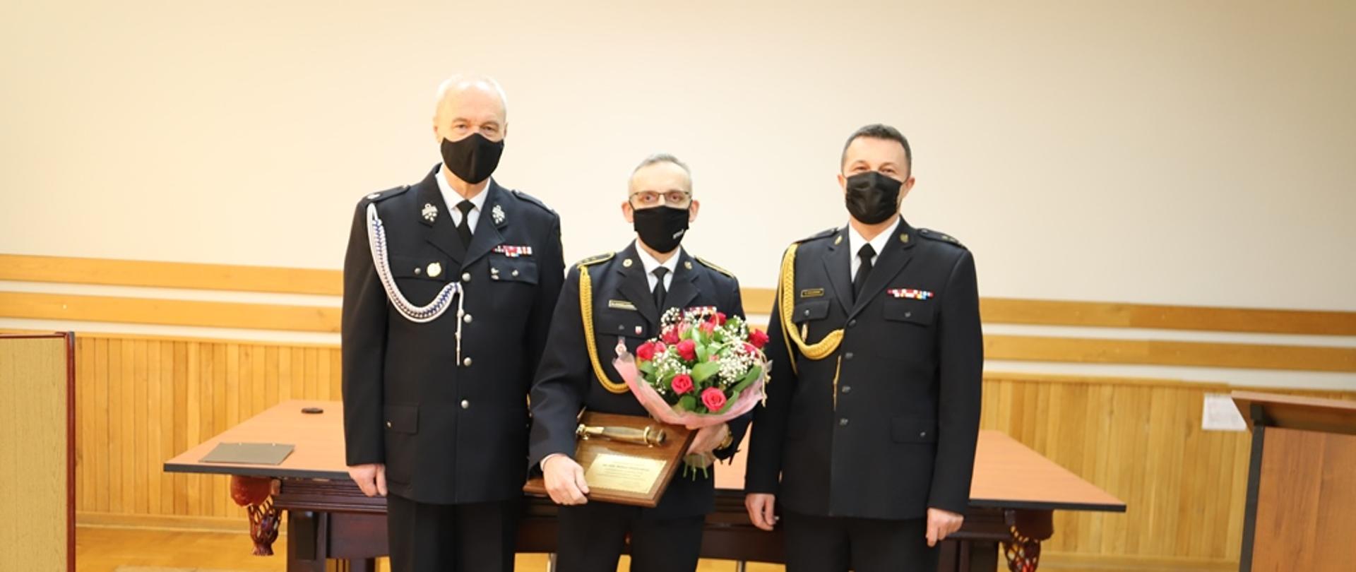 asp. sztab. Marek Chmielewski prezentujący pamiątkowy toporek, podczas uroczystej zbiórki związanej z przejściem na zaopatrzenie emerytalne.