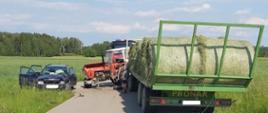 Uszkodzony samochód osobowy marki Audi oraz ciągnik rolniczy Ursus po zderzeniu czołowym. W aucie osobowym uszkodzone nadkole od strony kierowcy, lampa, zderzak oraz przednia szyba. W ciągniku urwane przednie koło. Za ciągnikiem przyczepa ze zbelowanym sianem.
