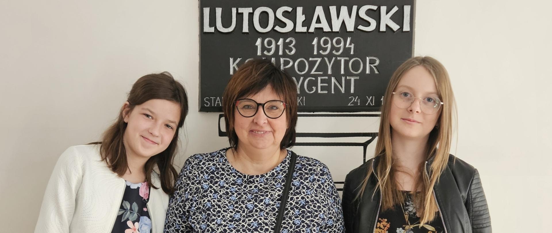 uczennice z nauczycielką, w tle tablica Lutosławskiego