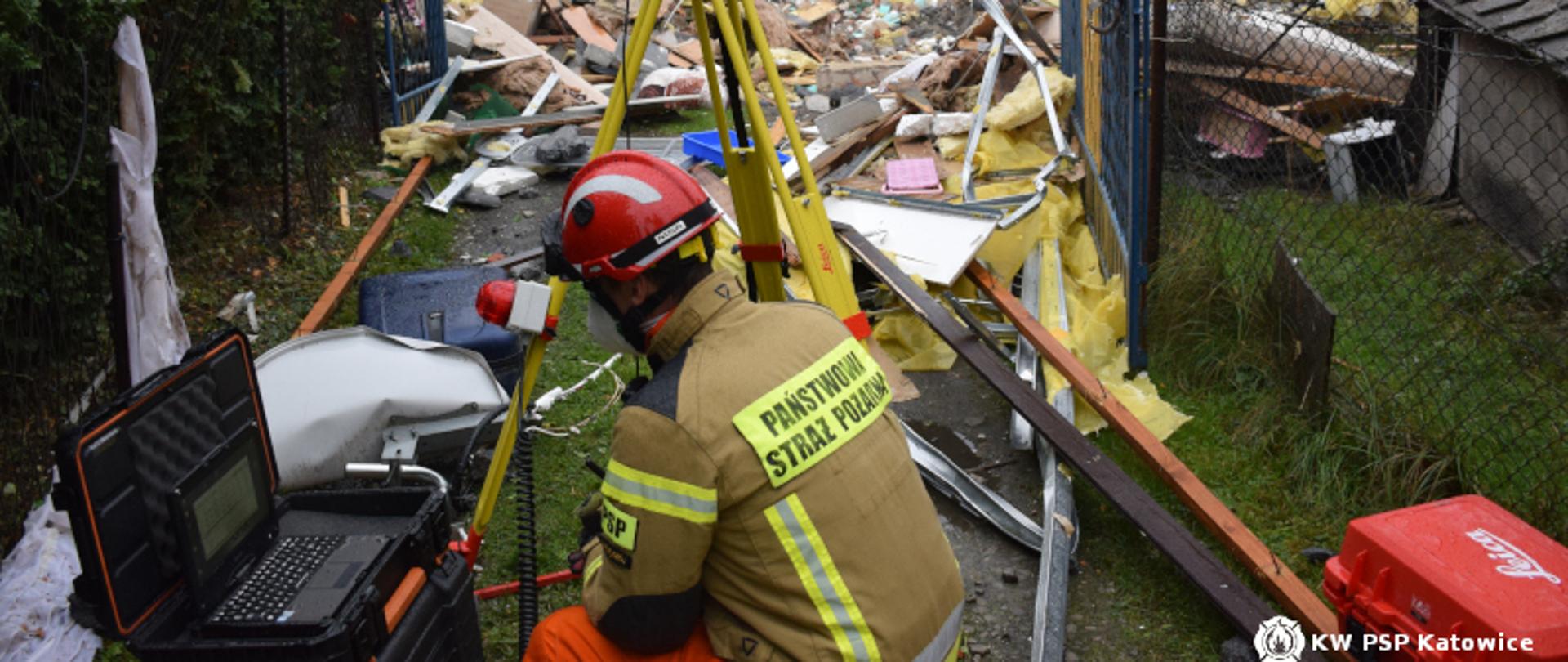 Na zdjęciu gruzowisko i strażak przy przyrządach pomiarowych.