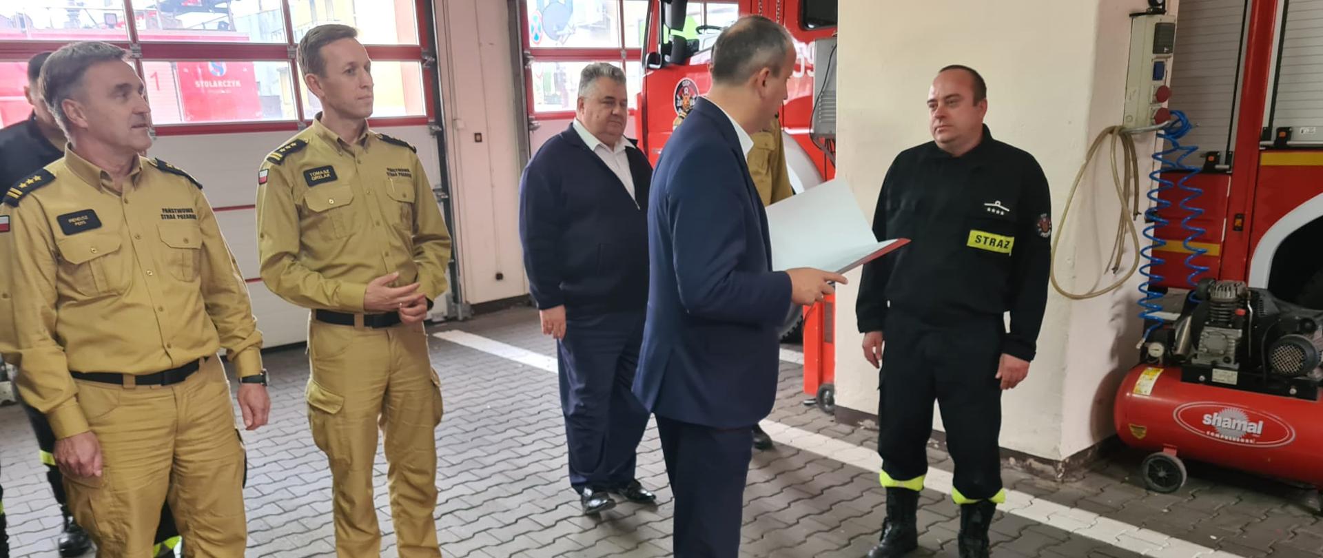 Zdjęcie przedstawia Wojewodę Wielkopolskiego z komendantami Państwowej Straży Pożarnej i Burmistrzem Pniew w garażu remizy Ochotniczej Straży Pożarnej w Pniewach