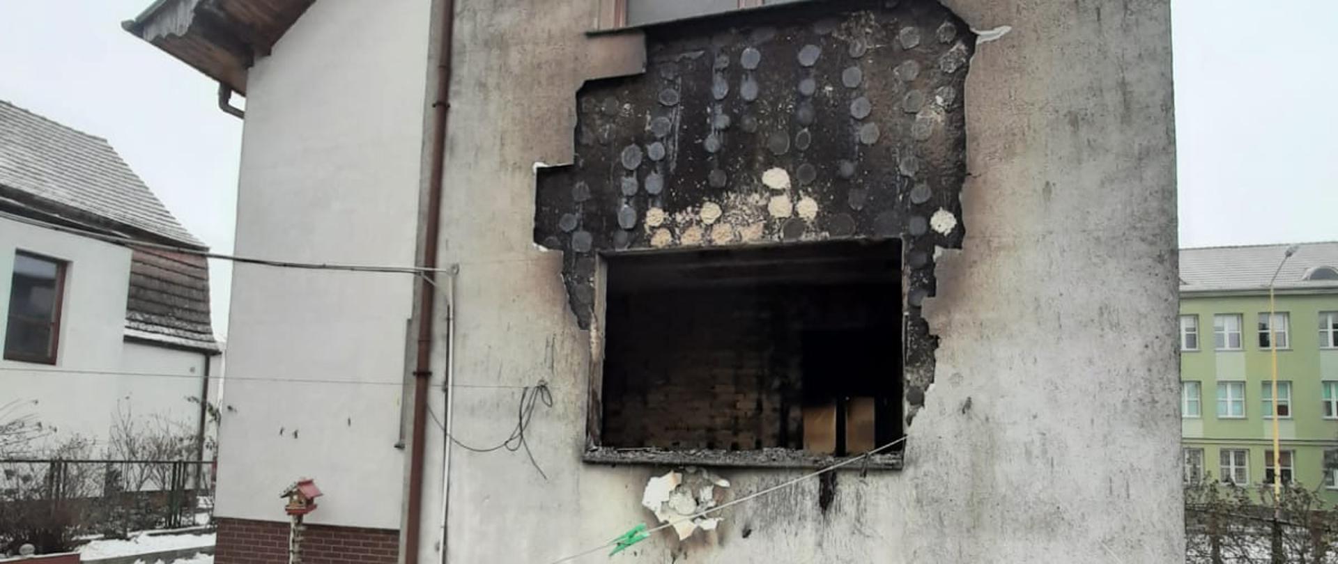 Widok elewacji budynku po pożarze. Widoczny otwór po wypalonym oknie.