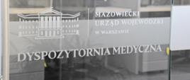 szklane drzwi z napisem Mazowiecki Urząd Wojewódzki w Warszawie Dyspozytornia Medyczna