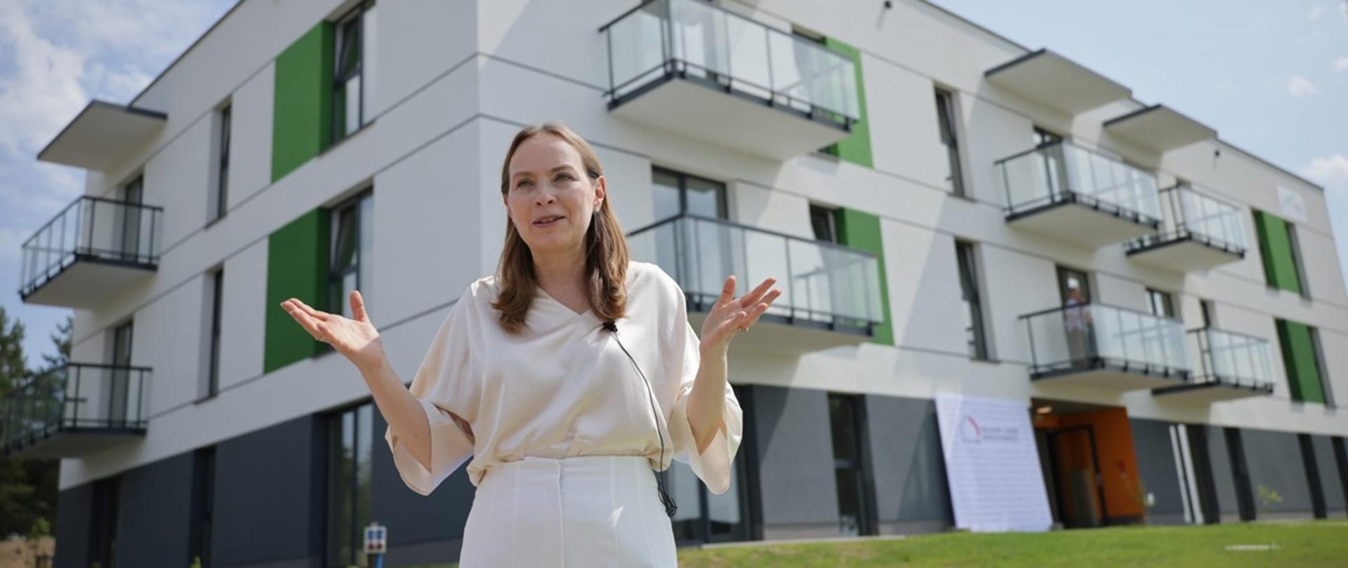 Minister funduszy i polityki regionalnej Katarzyna Pełczyńska-Nałęcz stoi przed budynkiem mieszkalnym w Kaczorach, wybudowanym w ramach SIM przez KZN Wielkopolska
