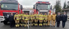 Zdjęcie grupowe Komendantów i strażaków na tle przekazywanych pojazdów. 