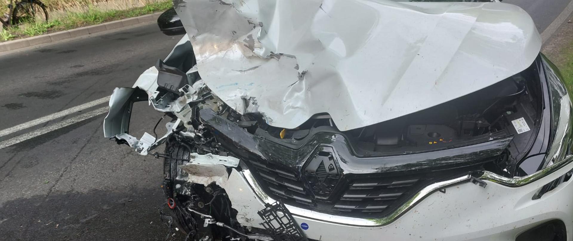 Zdjęcie przedstawia rozbity samochód po zderzeniu z motocyklem