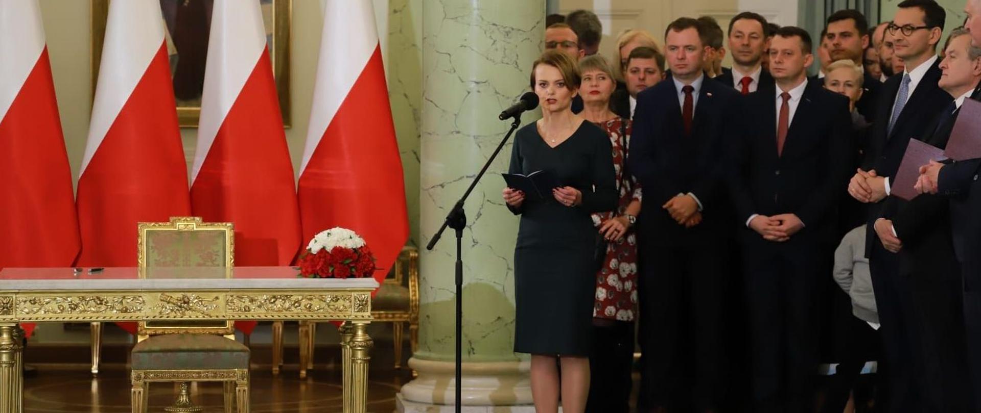 Min. Jadwiga emilewicz przed mikrofonem, w tle stojący ludzie