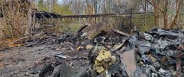 Zdjęcie przedstawia pozostałości hali magazynowej po pożarze oraz ponadpalane śmieci, które zostały usunięte z obiektu magazynowego