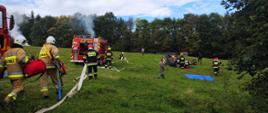 Na zdjęciu strażacy podczas ćwiczeń z gaszenia pożaru lasu, samochody pożarnicze, rozwinięte węże strażackie,
