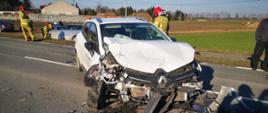 Widać uszkodzony samochód od przodu, jest na drodze