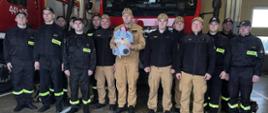 Strażacy KP PSP Opatów z przekazanym na aukcję misiem ratownikiem. W tle samochody pożarnicze
