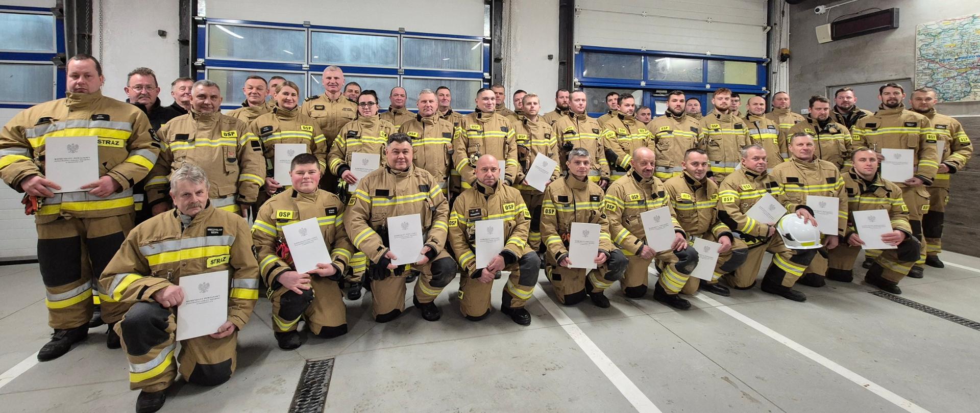 Strażacy pozują z dyplomami ukończenia kursu - garaż w JRG