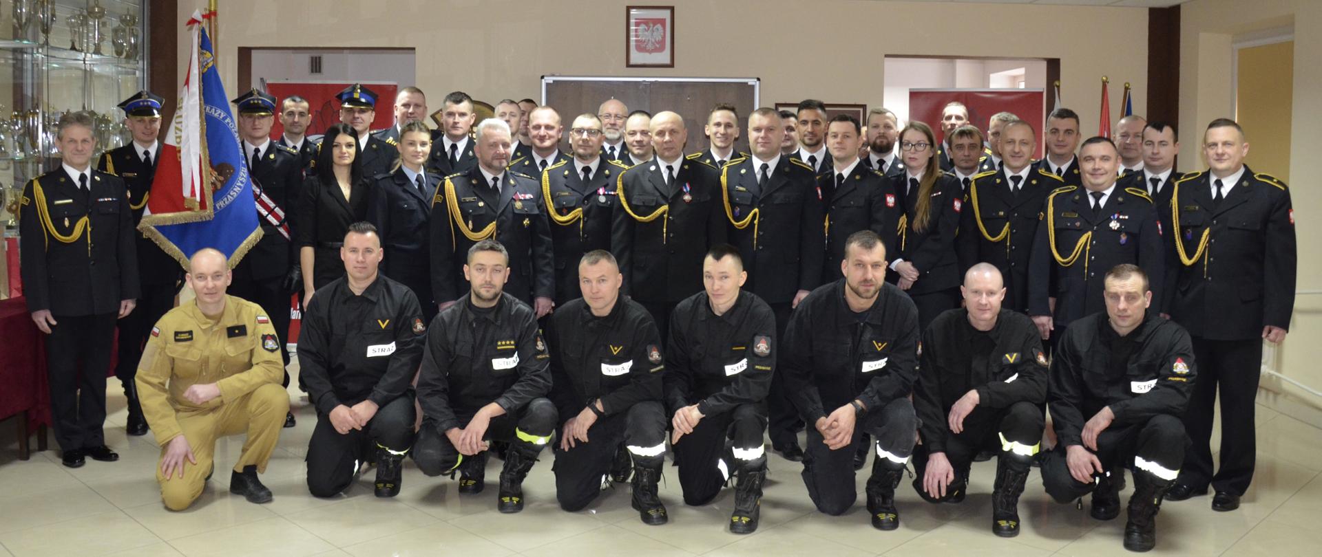 W dniu 2 lutego 2024 r. odbyła się uroczysta zbiórka, podczas której Komendant Powiatowy Państwowej Straży Pożarnej w Przasnyszu st. bryg. Waldemar Białczak, wraz z załogą pożegnał asp.sztab. Tomasza Kossaka oraz st.ogn. Jarosława Tadrzaka, którzy z dniem 31 stycznia 2024 r. przeszli na zasłużone zaopatrzenie emerytalne.
Uroczystość odbyła się w obecności Sztandaru Komendy Powiatowej PSP w Przasnyszu i licznie przybyłych koleżanek i kolegów, Życzącym świeżo upieczonym emerytom wszystkiego najlepszego na nowym etapie życia.
Na początku pożegnalnego spotkania głos zabrał Komendant Powiatowy st.bryg. Waldemar Białczak, który w imieniu swoim oraz wszystkich zgromadzonych podziękował funkcjonariuszom za ich poświęcenie, wielkie zaangażowanie i trud włożony w wykonywanie swoich obowiązków służbowych. Wspomniał o wielkim dorobku służbowym oraz na zakończeniu wręczył odchodzącym upominki.
________________________________________
asp.sztab. Tomasz Kossak służbę w ochronie przeciwpożarowej rozpoczął w 1997 r. jako stażysta w Komendzie Rejonowej Państwowej Straży Pożarnej w Przasnyszu. Po ukończeniu kursu podstawowego został mianowany na stanowisko młodszego ratownika. W 1999 roku został przeniesiony na stanowisko technika w Sekcji Kwatermistrzosko-Technicznej i podjął naukę w Szkole Podoficerskiej w Supraślu. Podczas swojej kariery zawodowej pogłębiał swoją wiedzę, której zwięczeniem było ukończenie Szkoły Aspirantów PSP w Krakowie w 2011 r. Podczas swojej służby ze względu na umiejętności, wiedze, wielkie zaangażowanie był mianowany na stanowiska wymagające odpowiednich predyspozycji między innymi na Powiatowym Stanowisku Kierowania, Sekcji Kontrolno-Rozpoznawczej i Samodzielnego Stanowiska ds. Kwatermistrzostwo Technicznych.
st.ogn. Jarosław Tadrzak po przebyciu postępowania kwalifikacyjnego rozpoczął służbę przygotowawczą w Komendzie Pwoatowej PSP w Przasnyszu w dniu 07.05.2001 r. na stanowisku stażysty. Następnie w latach 2001-2004 na stanowiskach młodszy ratownik kierowca i ratownik kierowca. Z dniem 1.12.2004 r. został mianowany na stanowisko operatora sprzętu specjalnego po czym w 2008 r. został straszy operatorem sprzętu specjalnego. Ze względu na swój staż, odpowiedzialność i wiedzę w roku 2023 mianowany został na dowódcę zastępu w JRG KP PSP w Przasnyszu.
Przez cały okres swej służby związany był z pionem operacyjnym JRG pełniąc funkcje na stanowiskach wymagających obsługi specjalistycznego sprzętu pożarniczego i posiadał do tego wszelkie uprawnienia i kwalifikacje. Był pracownikiem sumiennym, zdyscyplinowanym, dbał o powierzony sprzęt pożarniczy. Z obowiązków służbowych wywiązywał się wzorowo. Wyróżniał się poświęceniem podczas działań ratowniczo gaśniczych. Dzięki prezentowanym walorom zawodowym i postawie w służbie cieszył się dużym zaufaniem i uznaniem współpracowników oraz przełożonych.
________________________________________
Opracowanie: kpt. Piotr Kuligowski.
Zdjęcia: st. kpt. Michał Wiśniewski, asp. Rafał Sekuna.
