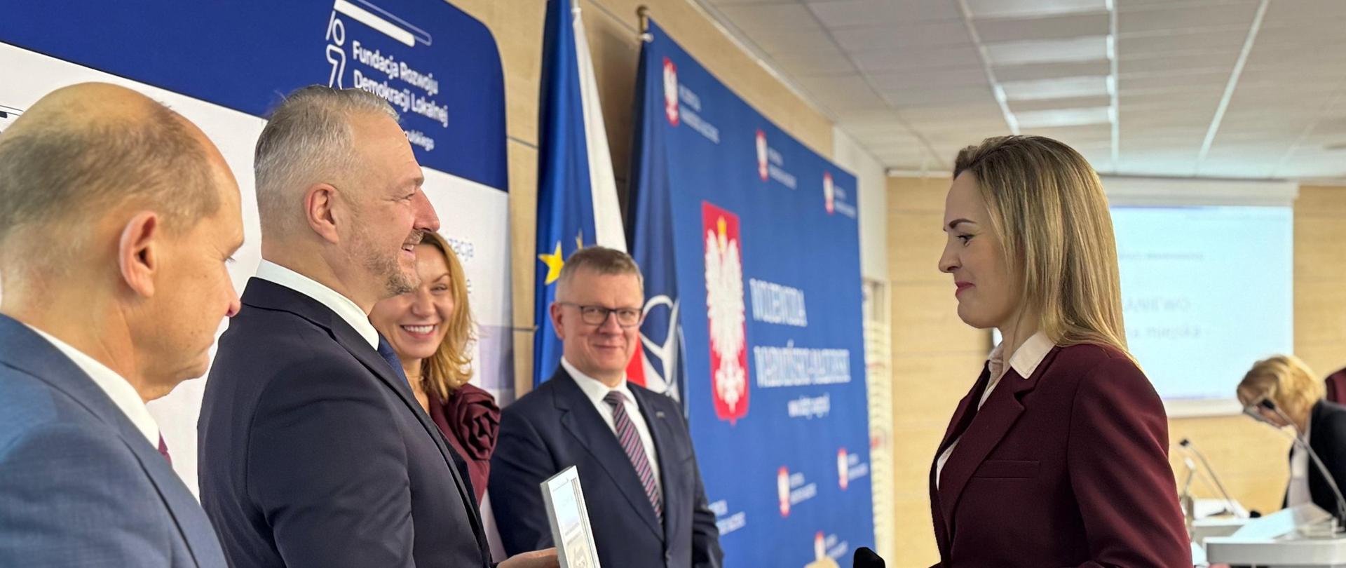 Kobieta odbiera z rąk mężczyzny dyplom 