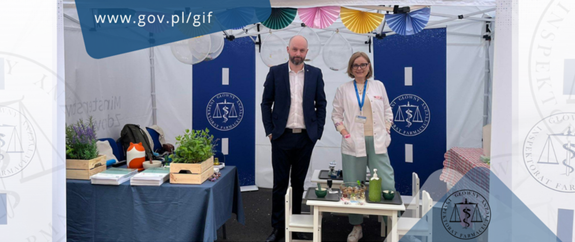 Główny Inspektor Farmaceutyczny Łukasz Pietrzak i dyrektor Biura Głównego Inspektora Farmaceutycznego Olga Sierpniowska stoją na stoisku GIF przygotowanym do pikniku z okazji Dnia Dziecka w Kancelarii Prezesa Rady Ministrów.