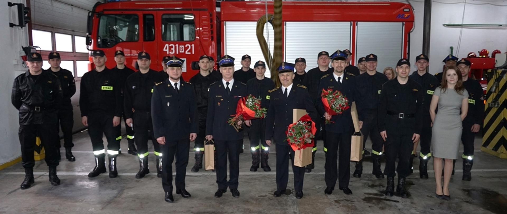 Pamiątkowe zdjęcie na tle czerwonego samochodu gaśniczego.