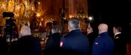 Funkcjonariusze służb mundurowych stoją podczas mszy świętej w kościele.